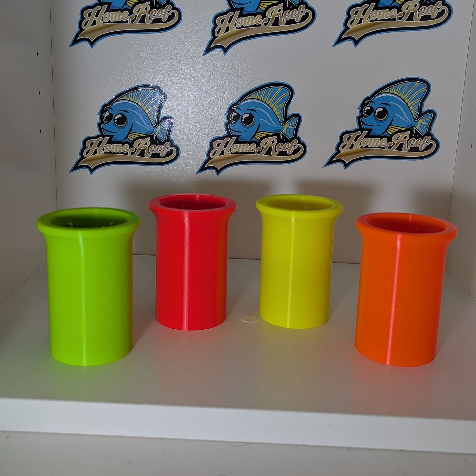Tang Feeder Innenzylinder für Salatblätter in verschiedenen Farben vor HomeReef-Logo.